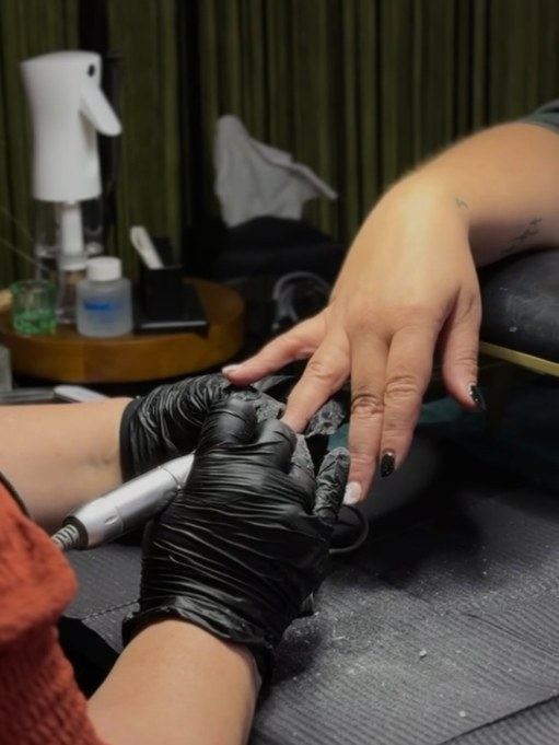 Kelly prepping a guest's natural nails with an e-file