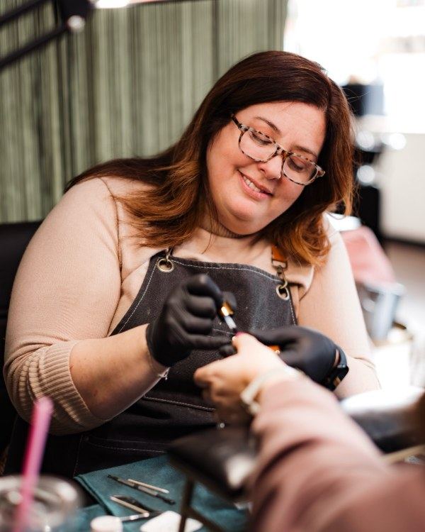 Kelly painting a guest's nails at her station