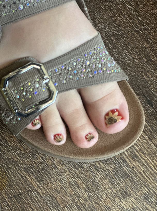 Pedicure with yellow polish and sunflower art in a sandal